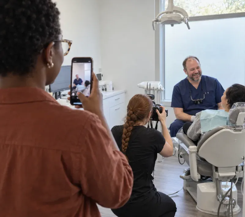 An agency founder filming a photo shoot at a client's dental clinic on her phone