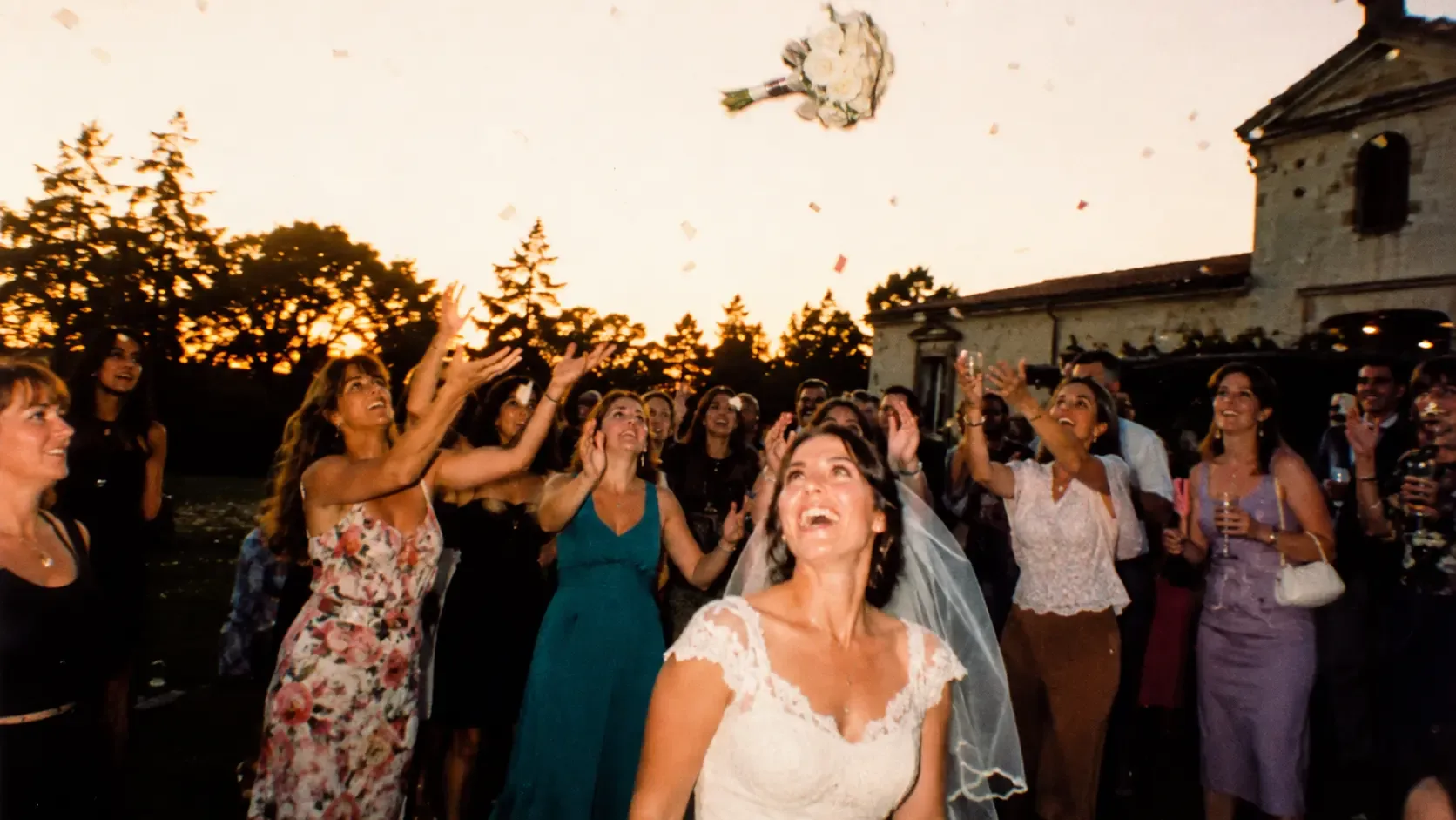 A bouquet flying through the air at a golden-hour wedding, the bride looking up