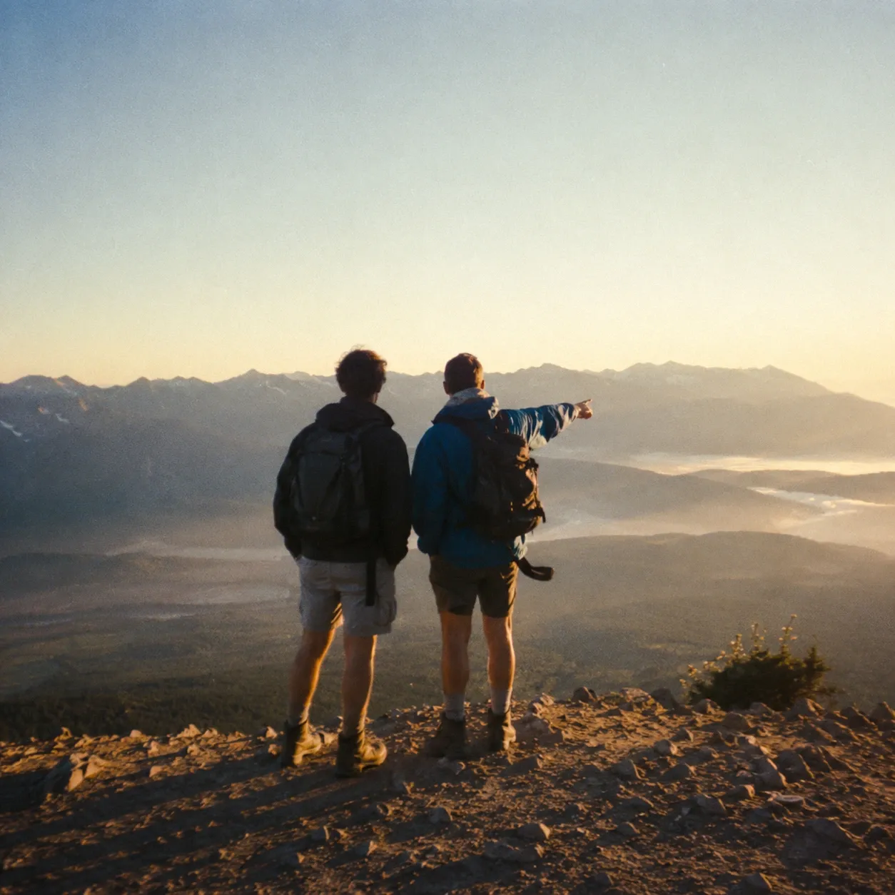 Two friends on a mountain ridge at sunrise